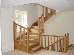 bespoke wooden staircase leading up from a landing with cream carpet.